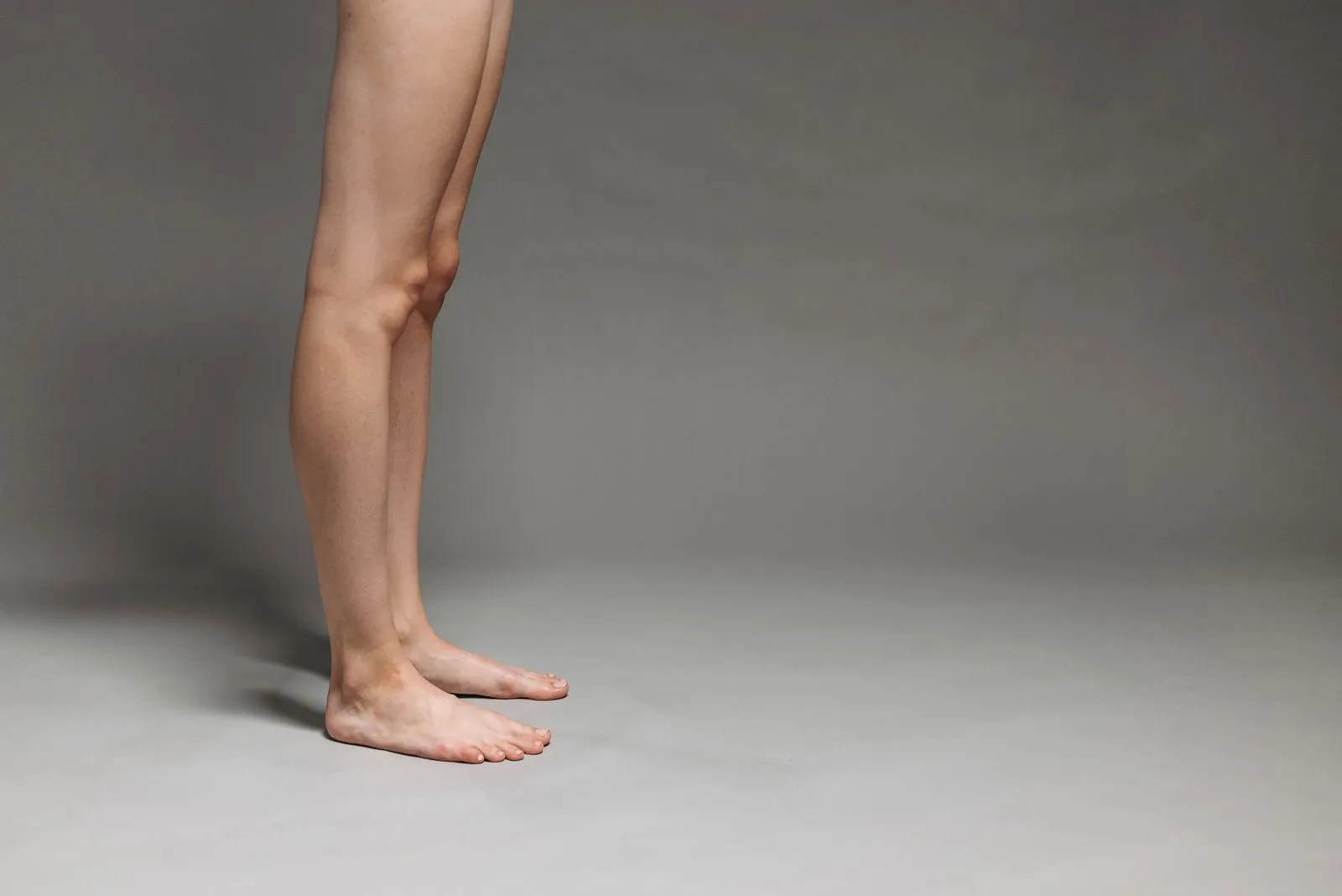 Studio shot of bare legs against a gray backdrop, focused on minimalist design.